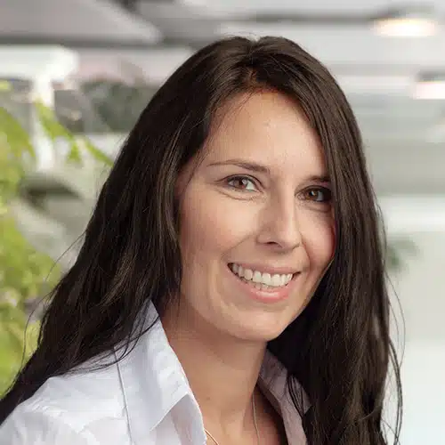 Gros plan de Gabriele Hillenbrand, une femme souriante avec de longs cheveux foncés portant une chemise blanche. Elle est Consultante commerciale / Service client chez Debatin.