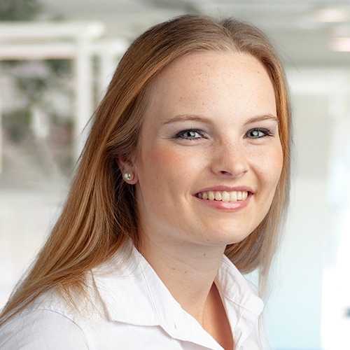 Portrait de Melina Hoffmann, une femme souriante aux cheveux mi-longs. Elle porte un chemisier blanc et paraît ouverte et amicale. Melina Hoffmann est employée chez DEBATIN.