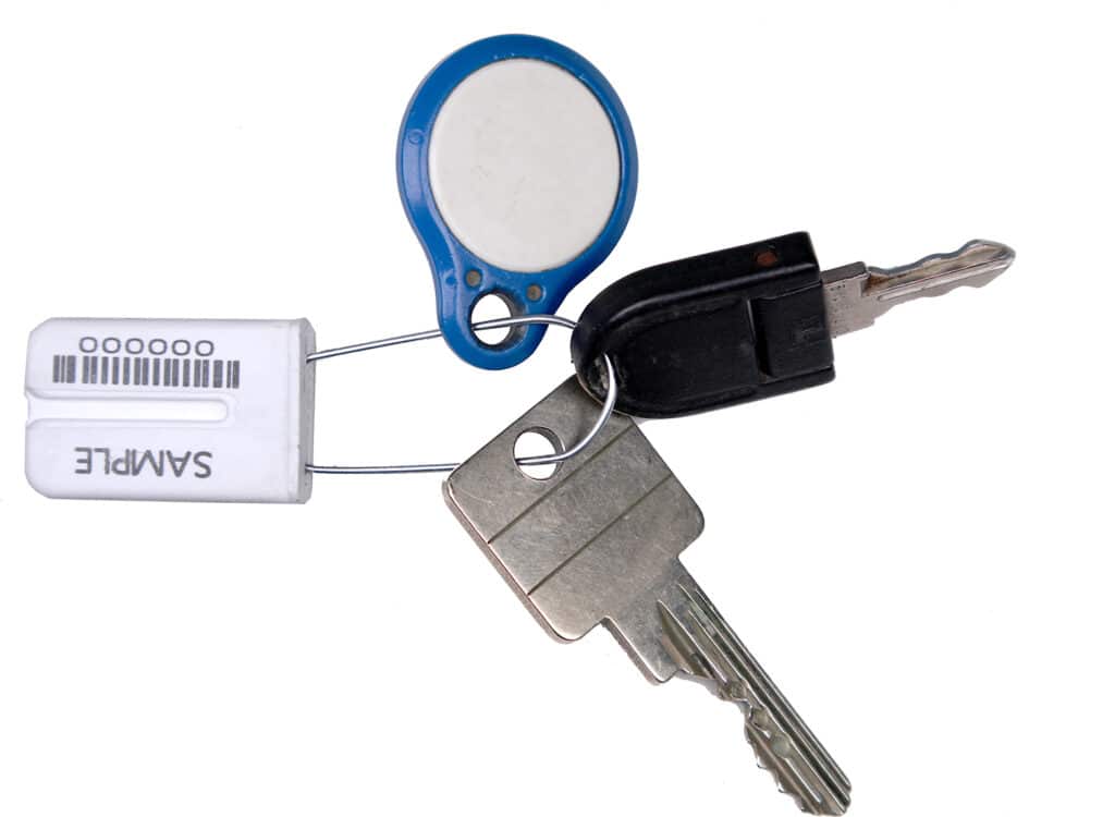 Porte-clés avec scellé de clé DEBASEAL® blanc, deux clés et badge RFID bleu sur fond blanc.