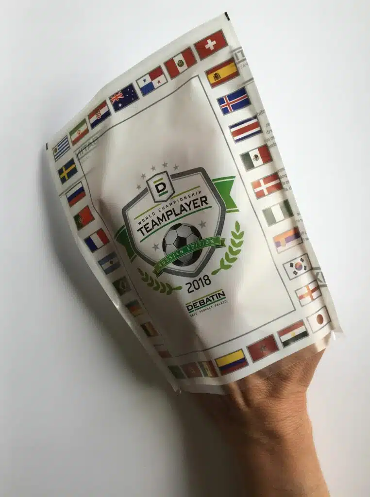 Cleanfix_Hand-1 Main tenant un sachet CLEANFIX® édition Teamplayer Coupe du Monde 2018, décoré de drapeaux et d’un emblème de football.