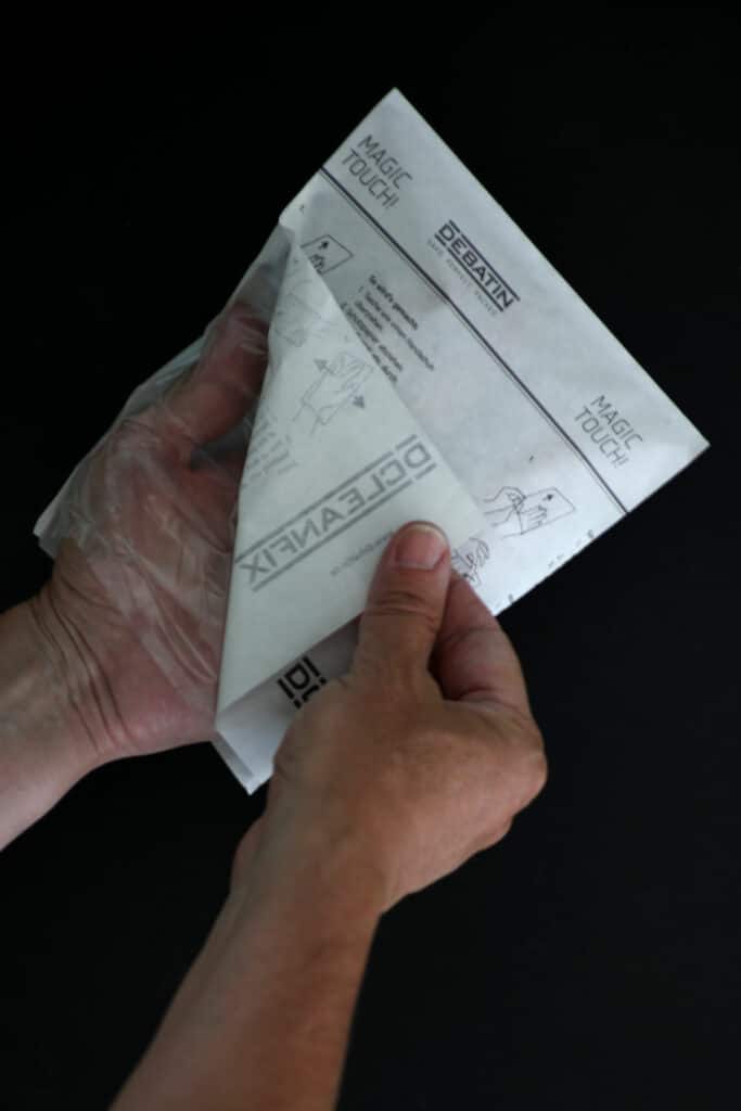 cleanfix_use Mains retirant le papier de protection d’un sachet CLEANFIX®, avec instructions d’utilisation et mention « Magic Touch! ».